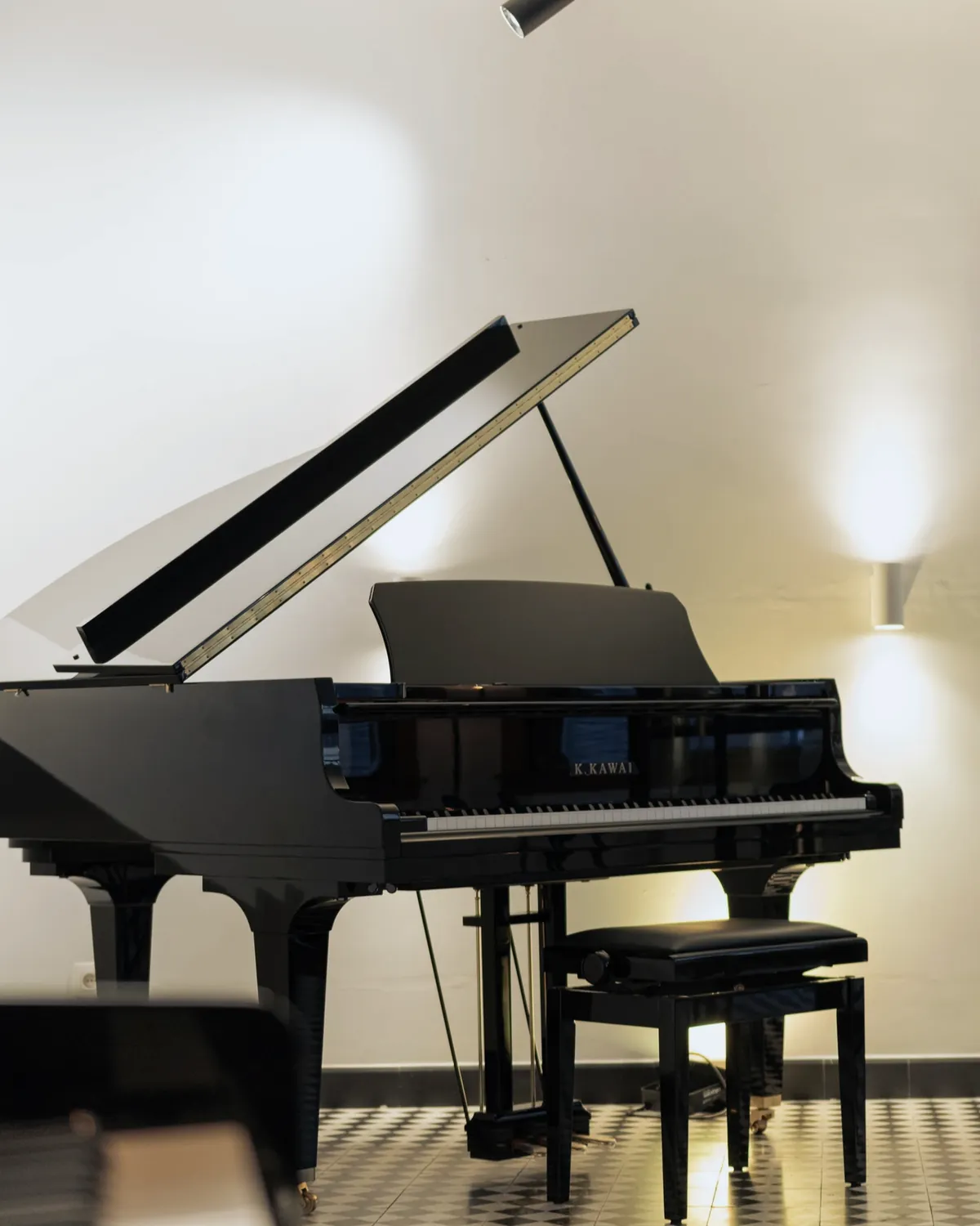 Een zwarte vleugel met open klep en pianobank in warm licht