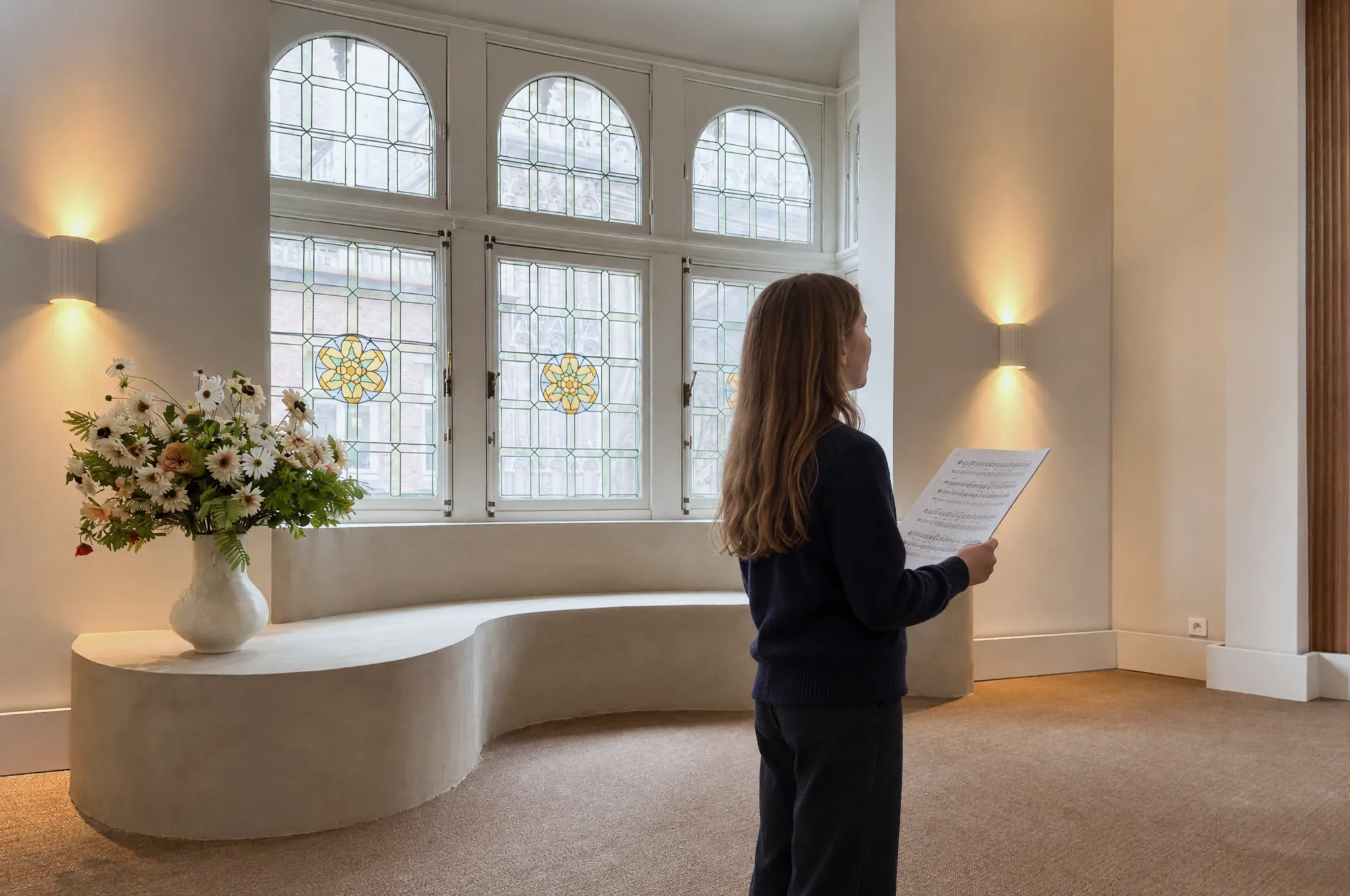 Een meisje zingt met een partituur in de hand in de salon van Huis Pollet tijdens een individuele zangles
